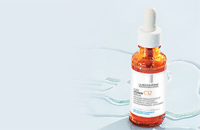 Flacon de serum avec pipette sur fond bleu clair.