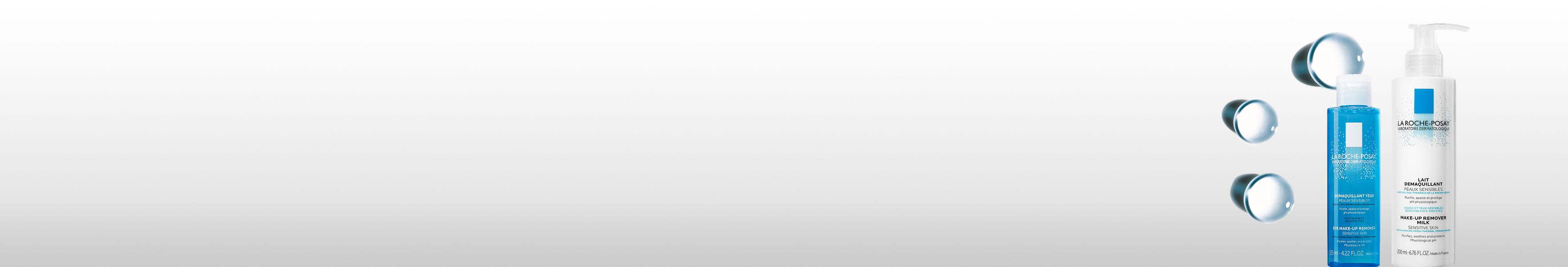 Alt text: "Trois flacons de produits de soins capillaires sur fond gris clair, avec des gouttes d'eau."