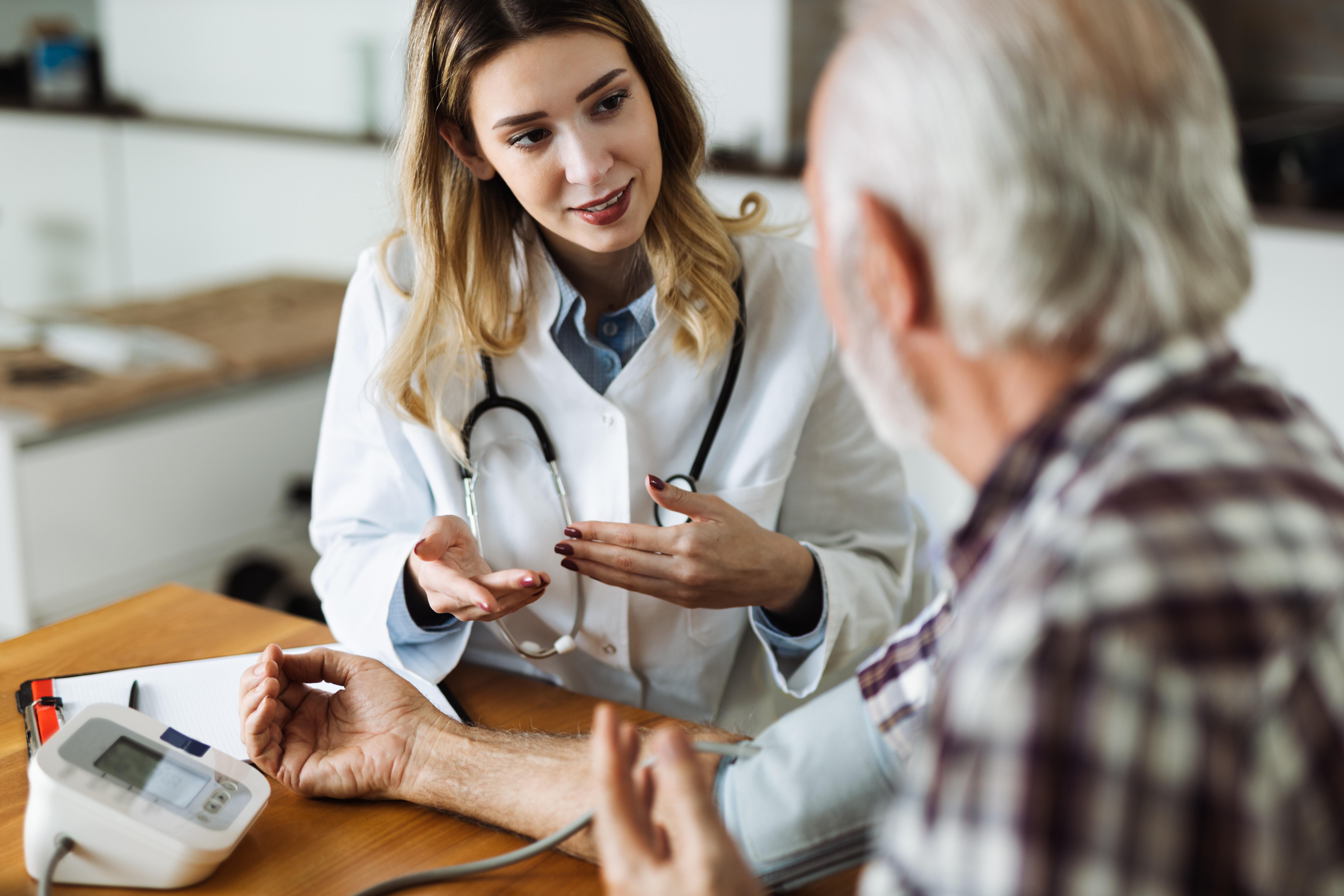 Une medecin parle a un patient age pendant une consultation medicale, avec un tensiometre sur la table.