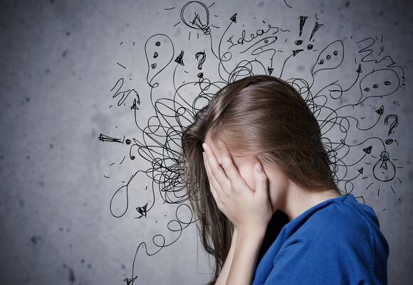 Une jeune fille se couvre le visage avec les mains, montrant des signes de stress ou d'anxiete, tandis que des doodles representant des idees et des questions tourbillonnent autour d'elle.